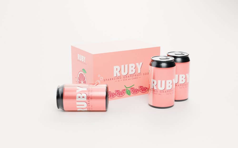 A six-pack of Ruby grapefruit soda rendered in Blender Cycles: a printed coral carton behind two labelled cans standing and one lying down, on a grey studio sweep